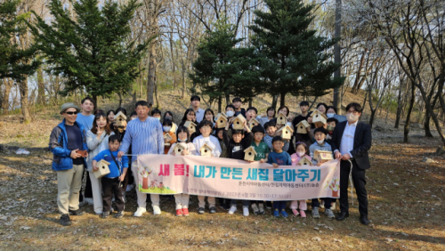 춘천 삼천동 생태체험공원에서 춘천지역아동센터와 한길지역아동센터 이용 아동 25명과 직원들이 서있고 어린이들이 직접 만든 새집모형과 양쪽에 남자 직원 두명이 맨앞에 서서 '새봄! 내가만든 새집 달아주기, 춘천지역아동센터/한길지역아동센터/(주)늘솜, 삼전동 생태체험공원 / 2023년 4월 3일 16