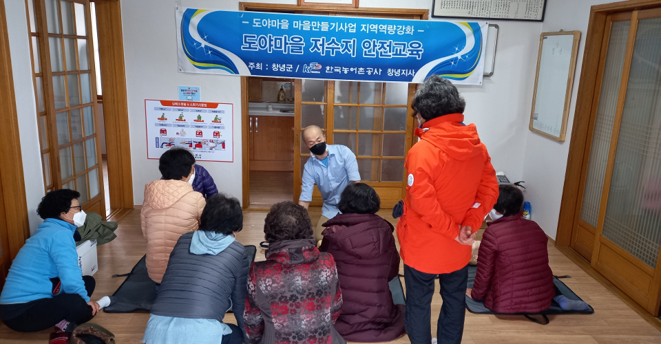 마을회관안에서 '도야마을 마을만들기사업 지역역량강화, 도야마을 저수지 안전교육' 현수막이 걸려있고 마을 주민들이 모여 안전교육을 받고있는 모습